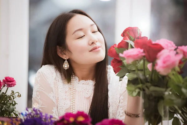 Kırmızı ve pembe gülleri budamaya hazırlanan kadın ve evdeki güzel çiçek aranjmanları Sevgililer Günü için vazoyla çiçek aranjmanları ve masada aile içi hediyeler.