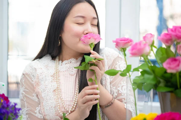 Kırmızı ve pembe gülleri budamaya hazırlanan bir kadın ve evdeki güzel çiçek aranjmanları, masadaki aile içinde Sevgililer Günü ve İş için vazo ile çiçek aranjmanları.