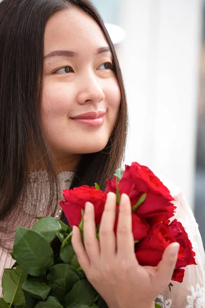 Kırmızı ve pembe gülleri budamaya hazırlanan kadın ve evdeki güzel çiçek aranjmanları Sevgililer Günü için vazoyla çiçek aranjmanları ve masada aile içi hediyeler.