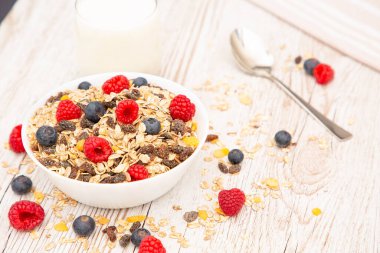 Kahvaltıda mısır gevreği, tam tahıl ve fincanda süt, çilek, böğürtlen, ahududu, ahududu, ahşap masada Kivi, diyet yemeği veya sabahları sağlıklı yemekle servis edilir..