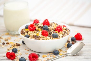 Kahvaltıda mısır gevreği, tam tahıl ve fincanda süt, çilek, böğürtlen, ahududu, ahududu, ahşap masada Kivi, diyet yemeği veya sabahları sağlıklı yemekle servis edilir..