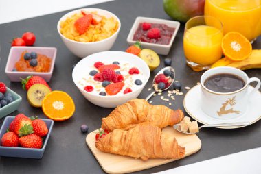 Kahvaltıda kahve, tereyağlı kruvasan, mısır gevreği, fincanda süt, çilek, ahududu, kivi ve kahvaltı masasında taze portakal suyu ile servis edilir..