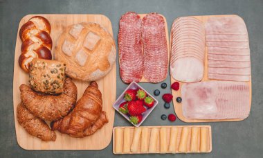 Sabah kahvaltı masada kruvasan ekmeği, kruvasan gevreği, pastırma, jambon, peynir, marul, fasulye, mısır gevreği, sağlıklı kahvaltı için meyve ve fotokopi alanı ile servis edilir.