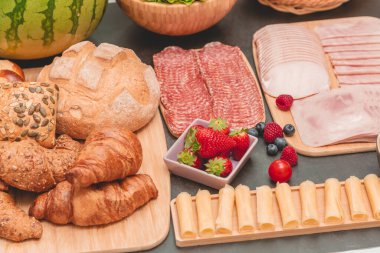 Sabah kahvaltı masada kruvasan ekmeği, kruvasan gevreği, pastırma, jambon, peynir, marul, fasulye, mısır gevreği, sağlıklı kahvaltı için meyve ve fotokopi alanı ile servis edilir.