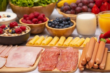 Sabah kahvaltısı sebze, kruvasan ekmeği, jambon, peynir, marul, fasulye, mısır gevreği ve meyveli olsun.