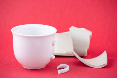 Kırık tabak, tabak ya da kırmızı arka planda kırık su bardağı. Mutfaktaki kaza kavramı, evin içindeki beden ve çocuklar için tehlikelidir..