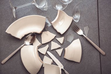 Mutfağın zemininde kırık tabaklar ya da kırık su bardakları. Mutfaktaki kaza kavramı, evin içindeki beden ve çocuklar için tehlikelidir..