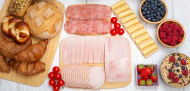 Sabah kahvaltı masada kruvasan ekmeği, kruvasan gevreği, pastırma, jambon, peynir, marul, fasulye, mısır gevreği, sağlıklı kahvaltı için meyve ve fotokopi alanı ile servis edilir.