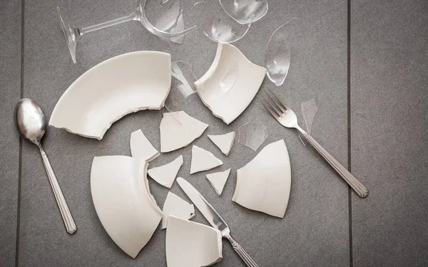 Mutfağın zemininde kırık tabaklar ya da kırık su bardakları. Mutfaktaki kaza kavramı, evin içindeki beden ve çocuklar için tehlikelidir..