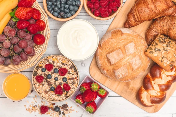 Kahvaltıda yanında tereyağlı kruvasan, mısır gevreği, fincanda süt, çilek, ahududu, kivi, kahvaltı masasında taze portakal suyu....