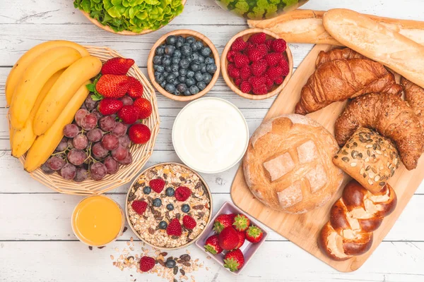 Kahvaltıda yanında tereyağlı kruvasan, mısır gevreği, fincanda süt, çilek, ahududu, kivi, kahvaltı masasında taze portakal suyu....