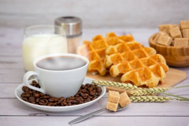 Sabah kahvaltısı, siyah kahve fincanı, ekmek, kruvasan ve ahşap masada meyve..