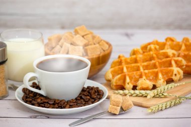 Sabah kahvaltısı, siyah kahve fincanı, ekmek, kruvasan ve ahşap masada meyve..