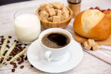 Sabah kahvaltısı, siyah kahve fincanı, ekmek, kruvasan ve ahşap masada meyve..