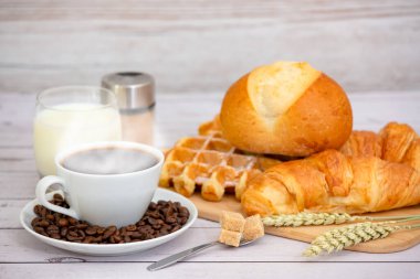 Sabah kahvaltısı, siyah kahve fincanı, ekmek, kruvasan ve ahşap masada meyve..