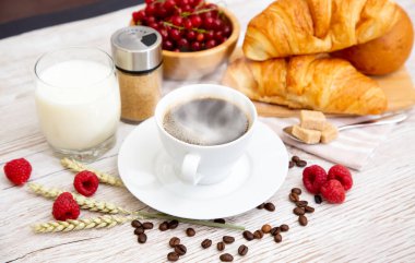 Sabah kahvaltısı, siyah kahve fincanı, ekmek, kruvasan ve ahşap masada meyve..