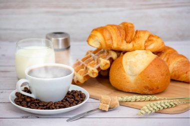 Sabah kahvaltısı, siyah kahve fincanı, ekmek, kruvasan ve ahşap masada meyve..