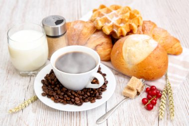 Sabah kahvaltısı, siyah kahve fincanı, ekmek, kruvasan ve ahşap masada meyve..