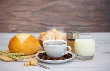 Sabah kahvaltısı, siyah kahve fincanı, ekmek, kruvasan ve ahşap masada meyve..