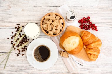 Sabah kahvaltısı, siyah kahve fincanı, ekmek, kruvasan ve ahşap masada meyve..