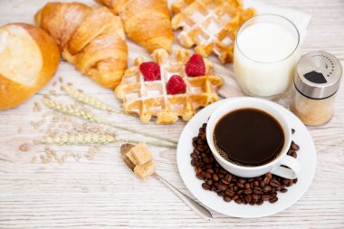Sabah kahvaltısı, siyah kahve fincanı, ekmek, kruvasan ve ahşap masada meyve..