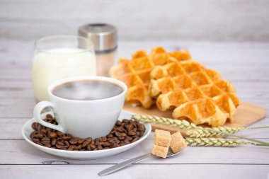 Sabah kahvaltısı, siyah kahve fincanı, ekmek, kruvasan ve ahşap masada meyve..