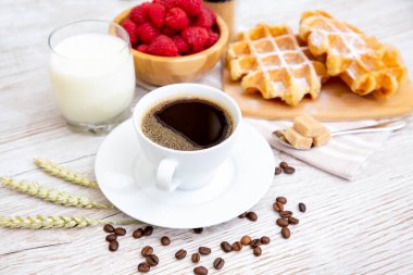 Sabah kahvaltısı, siyah kahve fincanı, ekmek, kruvasan ve ahşap masada meyve..