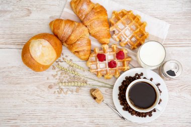 Sabah kahvaltısı, siyah kahve fincanı, ekmek, kruvasan ve ahşap masada meyve..