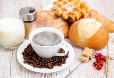 Sabah kahvaltısı, siyah kahve fincanı, ekmek, kruvasan ve ahşap masada meyve..