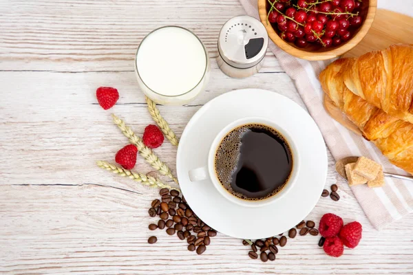 Sabah kahvaltısı, siyah kahve fincanı, ekmek, kruvasan ve ahşap masada meyve..