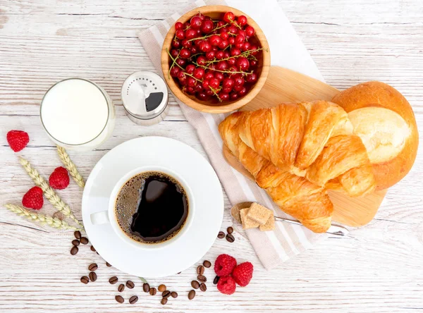 Sabah kahvaltısı, siyah kahve fincanı, ekmek, kruvasan ve ahşap masada meyve..