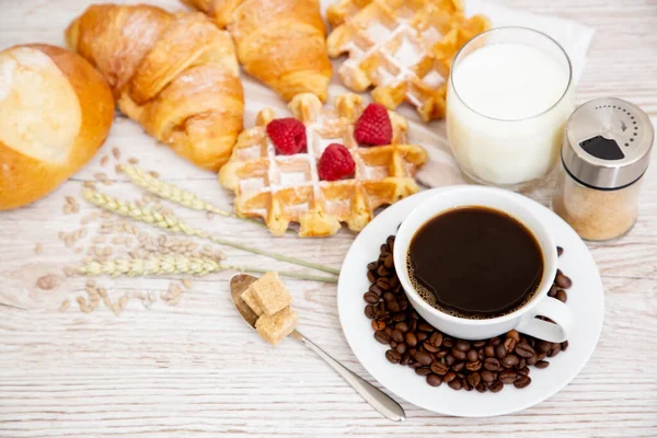 Sabah kahvaltısı, siyah kahve fincanı, ekmek, kruvasan ve ahşap masada meyve..