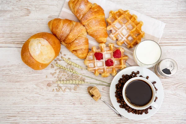 Sabah kahvaltısı, siyah kahve fincanı, ekmek, kruvasan ve ahşap masada meyve..