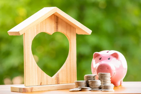 Happy Pink Piggy Bank and Home wooden in close-up and coins stack in the nature background, Saving ideas  and investment budget, Business saving money concept, Copy space