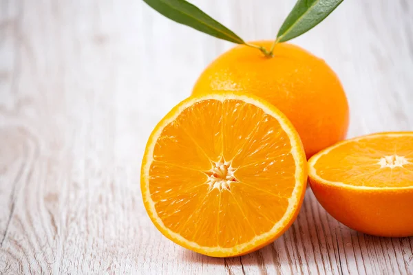 Ahşap arka planda doğal taze meyve portakalları, yarım kesilmiş portakal, portakal suyu, günlük sağlık için C vitamini.