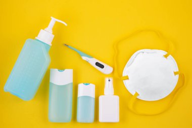 Mikrop korumalı Coronavirus veya covid19 ve jel alkolü veya el dezenfektanı şişesi takmak için maske, sarı arka planda izole edilmiş doktor ve hastaneler için ateş gözlemi.