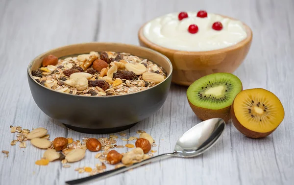 Biyolojik meyveli böğürtlen, ahşap kase içinde ve doğal yoğurt, kivi, ahududu, ve sağlık ve diyet için fındık ve ahşap masada C vitamini yakın plan..