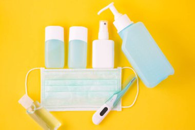 Doktor Maske mikrop korumalı Coronavirus ya da covid 19 ve jel alkolü ya da el yıkama için el dezenfektanı şişesi, sarı arka plandaki doktor hastaneleri için ateş monitörü.