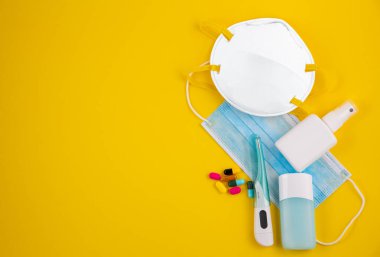 Doktor Maske, mikrop koruması için N95 maskesi Coronavirus veya Coperid 19 ve jel alkolü ya da el temizleme için el dezenfektanı şişesi, sarı arka plandaki doktor hastaneleri için ateş monitörü..