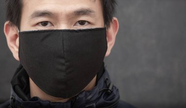 Siyah arkaplanda Başbakan 2.5 toz ve sis mikrobu, zehirli duman ve toz, bakteri enfeksiyonunun önlenmesi veya Covid 19 'u önlemek için bez maske takan Asyalı adamın yüzü.