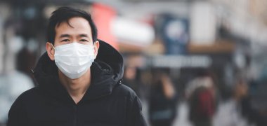 Mikropları, zehirli dumanları ve tozu önlemek için maske takan genç bir Asyalı kadının görüntüsü. Bakteriyel enfeksiyonun önlenmesi Corona virüsü veya Covid 19 sokaklarda ve bahçelerde.