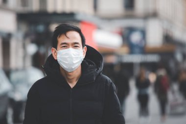 Mikropları, zehirli dumanları ve tozu önlemek için maske takan genç bir Asyalı kadının görüntüsü. Bakteriyel enfeksiyonun önlenmesi Corona virüsü veya Covid 19 sokaklarda ve bahçelerde.
