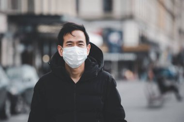 Mikropları, zehirli dumanları ve tozu önlemek için maske takan genç bir Asyalı kadının görüntüsü. Bakteriyel enfeksiyonun önlenmesi Corona virüsü veya Covid 19 sokaklarda ve bahçelerde.