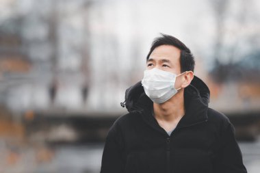Mikropları, zehirli dumanları ve tozu önlemek için maske takan genç bir Asyalı kadının görüntüsü. Bakteriyel enfeksiyonun önlenmesi Corona virüsü veya Covid 19 sokaklarda ve bahçelerde.