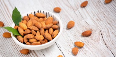 Beyaz bardakta tuzla karıştırılmış badem fıstıkları, tahıl arka planında protein yiyecekleri ve kilo vermek için sağlıklı gıdalar..