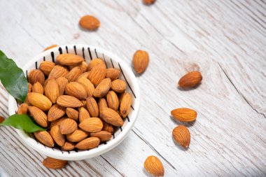 Beyaz bardakta tuzla karıştırılmış badem fıstıkları, tahıl arka planında protein yiyecekleri ve kilo vermek için sağlıklı gıdalar..