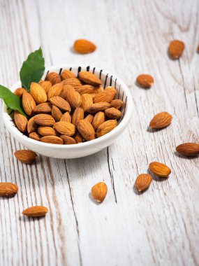 Beyaz bardakta tuzla karıştırılmış badem fıstıkları, tahıl arka planında protein yiyecekleri ve kilo vermek için sağlıklı gıdalar..