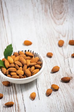 Beyaz bardakta tuzla karıştırılmış badem fıstıkları, tahıl arka planında protein yiyecekleri ve kilo vermek için sağlıklı gıdalar..