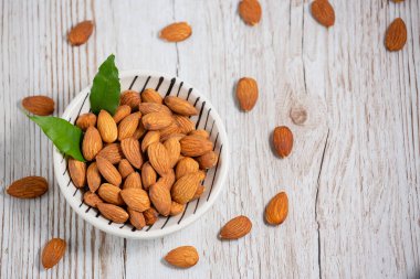 Beyaz bardakta tuzla karıştırılmış badem fıstıkları, tahıl arka planında protein yiyecekleri ve kilo vermek için sağlıklı gıdalar..