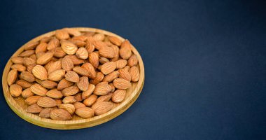 Badem fıstığı karışık tuz, siyah bir zemin üzerinde ahşap bir tabakta diyet yemeği ve protein yiyeceğidir..